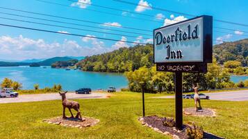 A sign for Deerfield Inn with a view of a lake and mountains in the background.