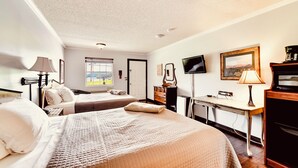 A hotel room with two beds, a desk, a television, and a view of the outdoors. - Deerfield Inn - Two Queen Beds - Pet Friendly (Hayesville)
