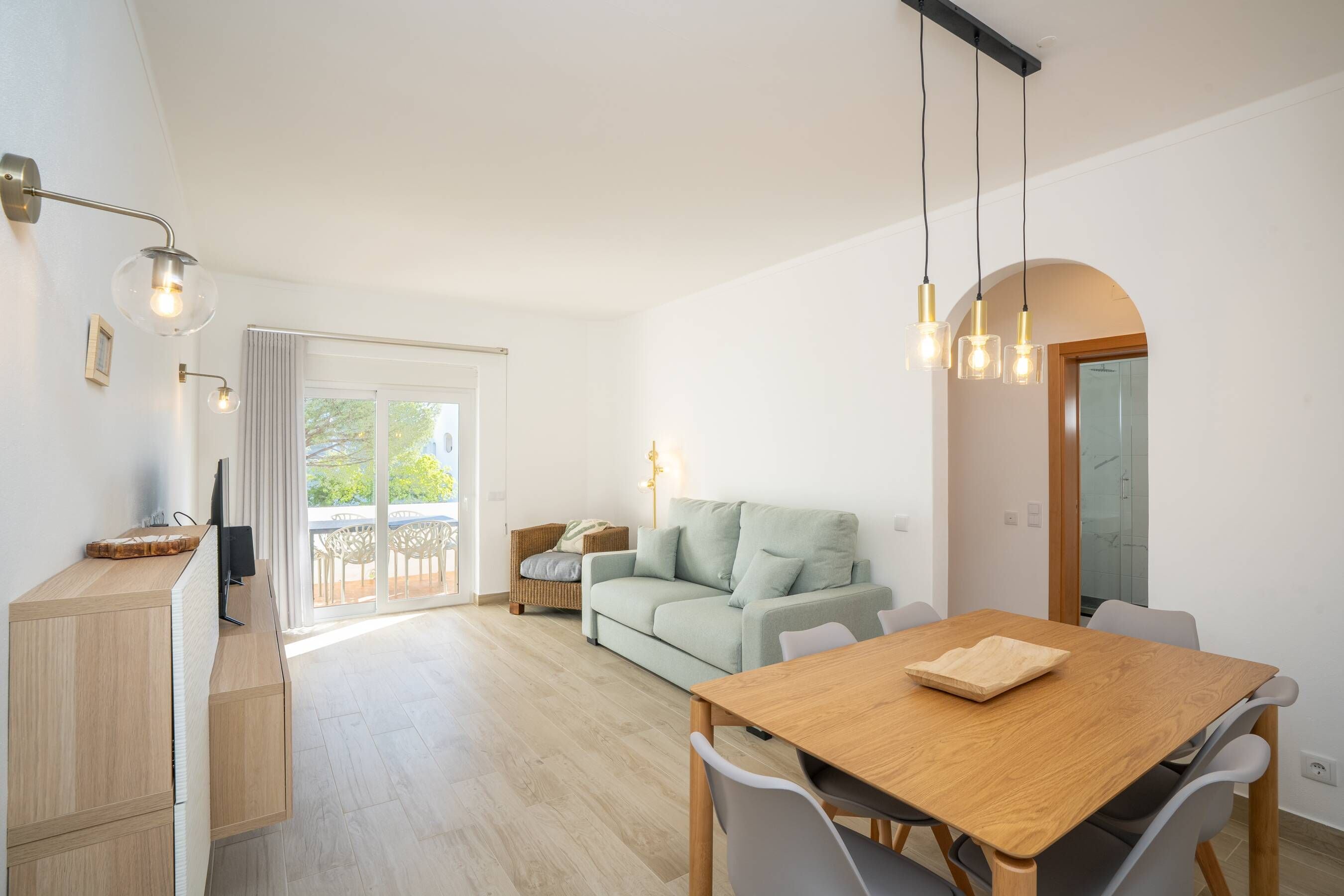 Et moderne opholdsrum med et træbord, en sofa og en balkon med havemøbler.