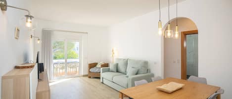 Et moderne opholdsrum med et træbord, en sofa og en balkon med havemøbler.