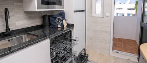 Une cuisine moderne équipée d’un four à micro-ondes encastré, d’un évier en acier inoxydable et d’un lave-vaisselle.