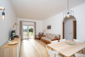 Ein modernes Wohnzimmer mit Essbereich, einer Couch, einem Fernseher und einem Tisch.