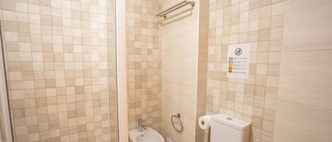 A bathroom with a bidet, toilet, and a towel.