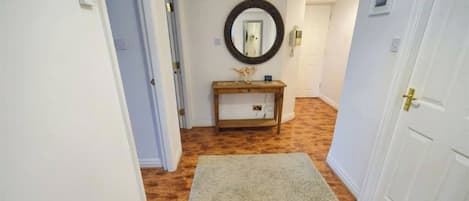 A hallway with a wooden console table, a mirror, and a rug.