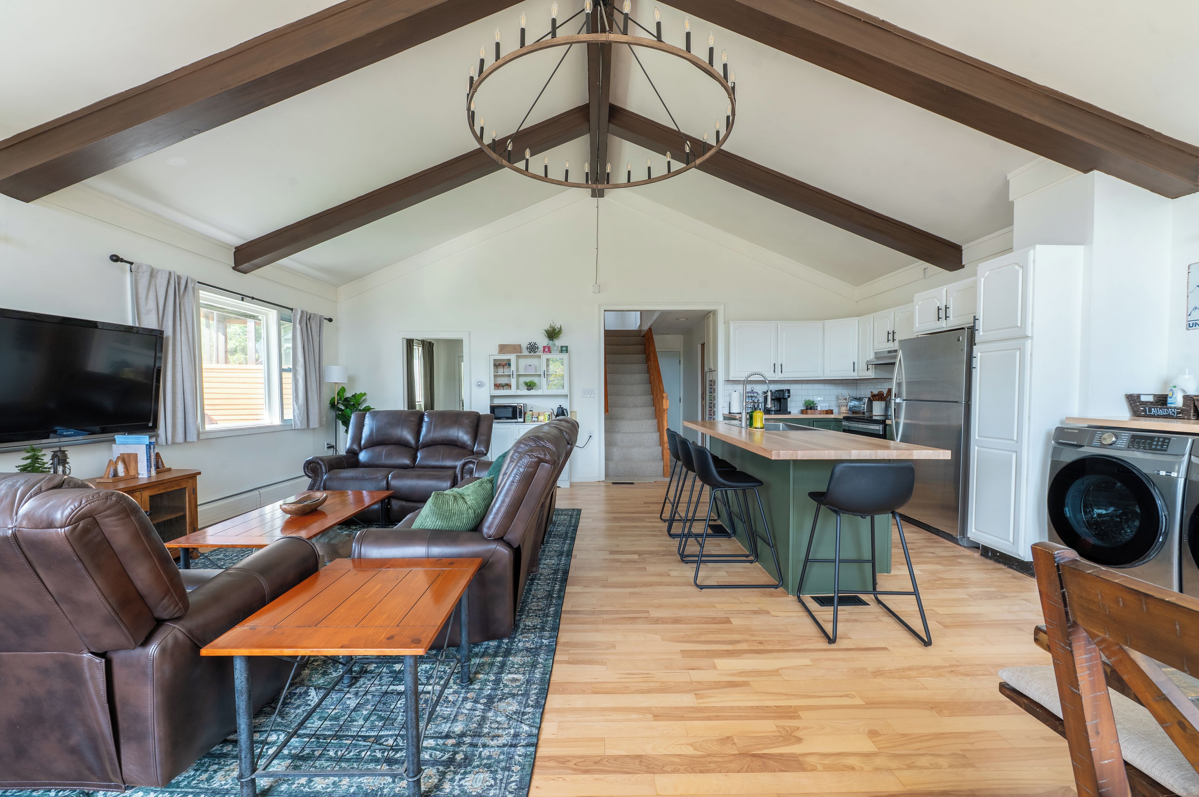 A spacious living area with a brown leather sofa, a wooden coffee table, and a television.