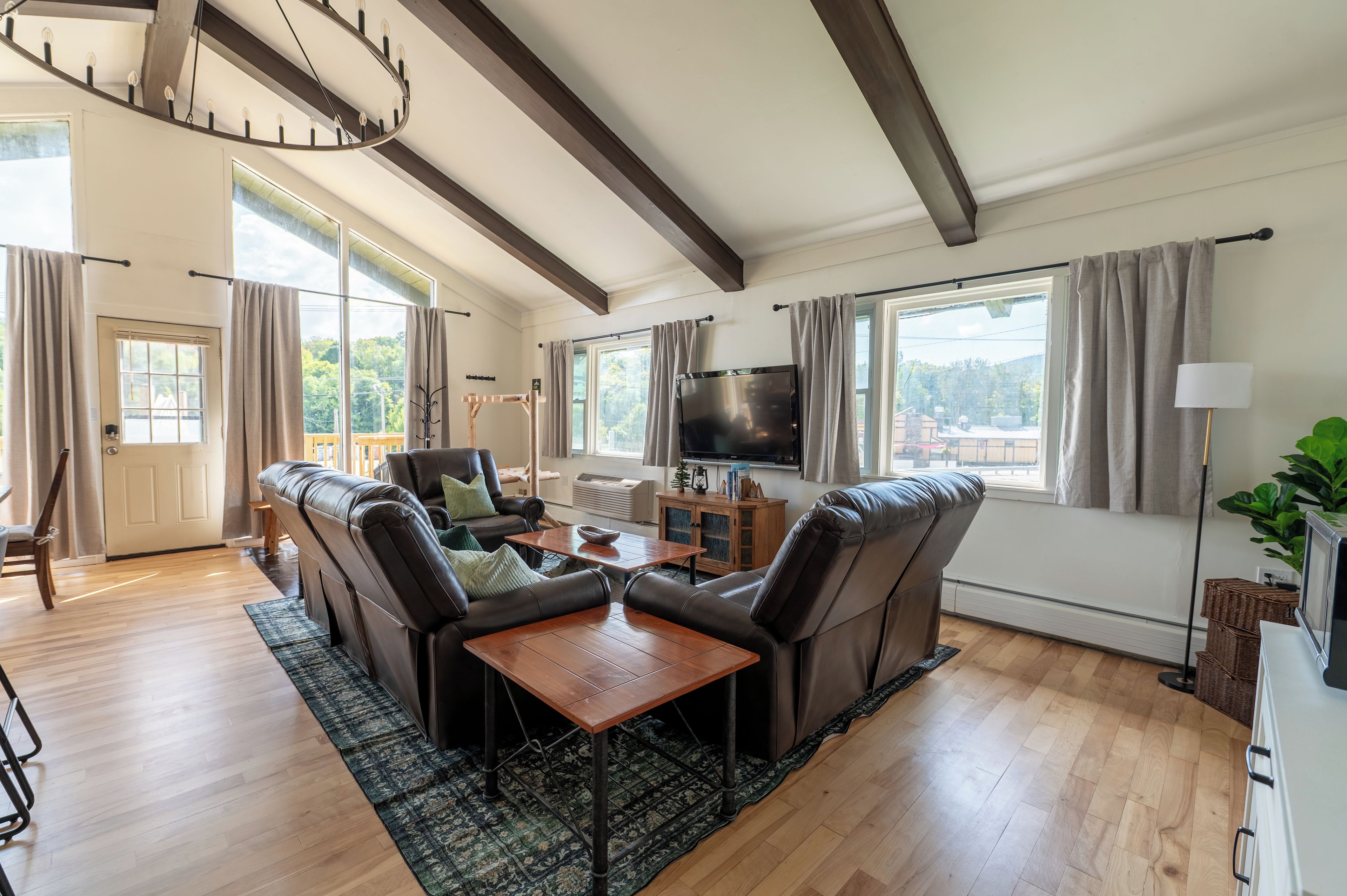 A spacious living room with a fireplace, leather sofas, a wooden coffee table, and a large flat-screen TV.