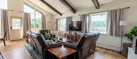 A spacious living room with a fireplace, leather sofas, a wooden coffee table, and a large flat-screen TV.
