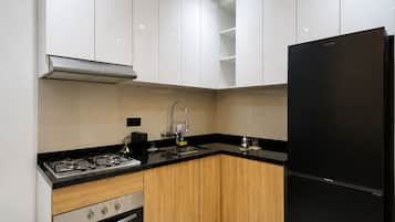 Eine moderne Küche mit weißen Schränken, einem schwarzen Kühlschrank, einem Herd und einem Backofen.