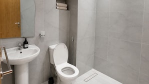 Et moderne badeværelse med hvid vask, toilet og bruseniche.