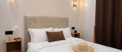 A bedroom with a large bed, bedside tables, wall-mounted lights, an air conditioning unit, and a window with curtains.