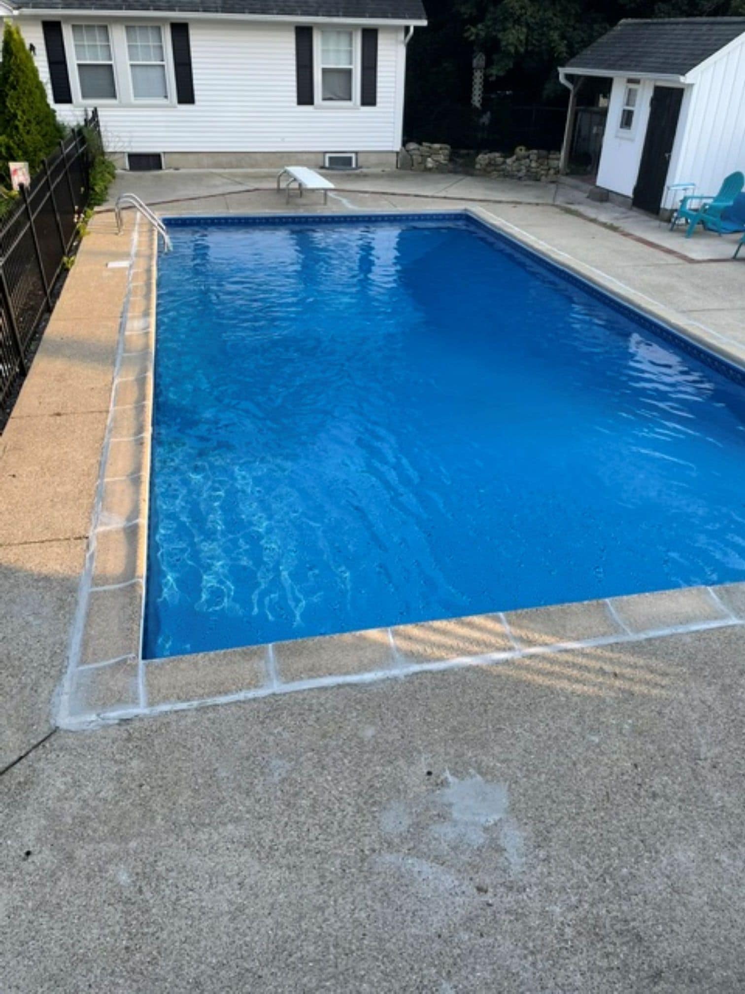 A rectangular swimming pool with a clear blue water surface, surrounded by a concrete deck.