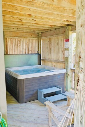 Een houten blokhut met een jacuzzi, een houten terras en een waarschuwingsbord.