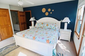 A bedroom with a bed, bedside tables, a nightstand, a ceiling fan, and a door. - Safe and Sound | Soundfront Corolla Light Retreat (Corolla)