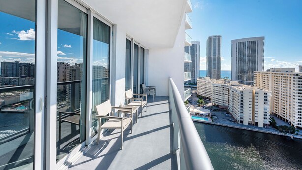 Ein Balkon mit großen Fenstern, einem Geländer und Blick auf Stadt und Wasser.