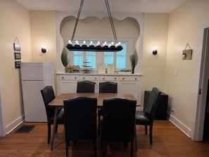 A dining area with a wooden table and black chairs, a white refrigerator, and a window with curtains. - 3-bedroom house in tranquil Champaign with air conditioning (Champaign)