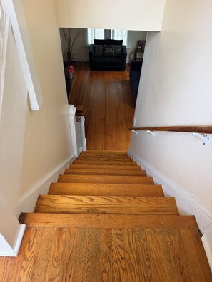 A wooden staircase leading to a living area with a sofa and decorative pillows. - 3-bedroom house in tranquil Champaign with air conditioning (Champaign)