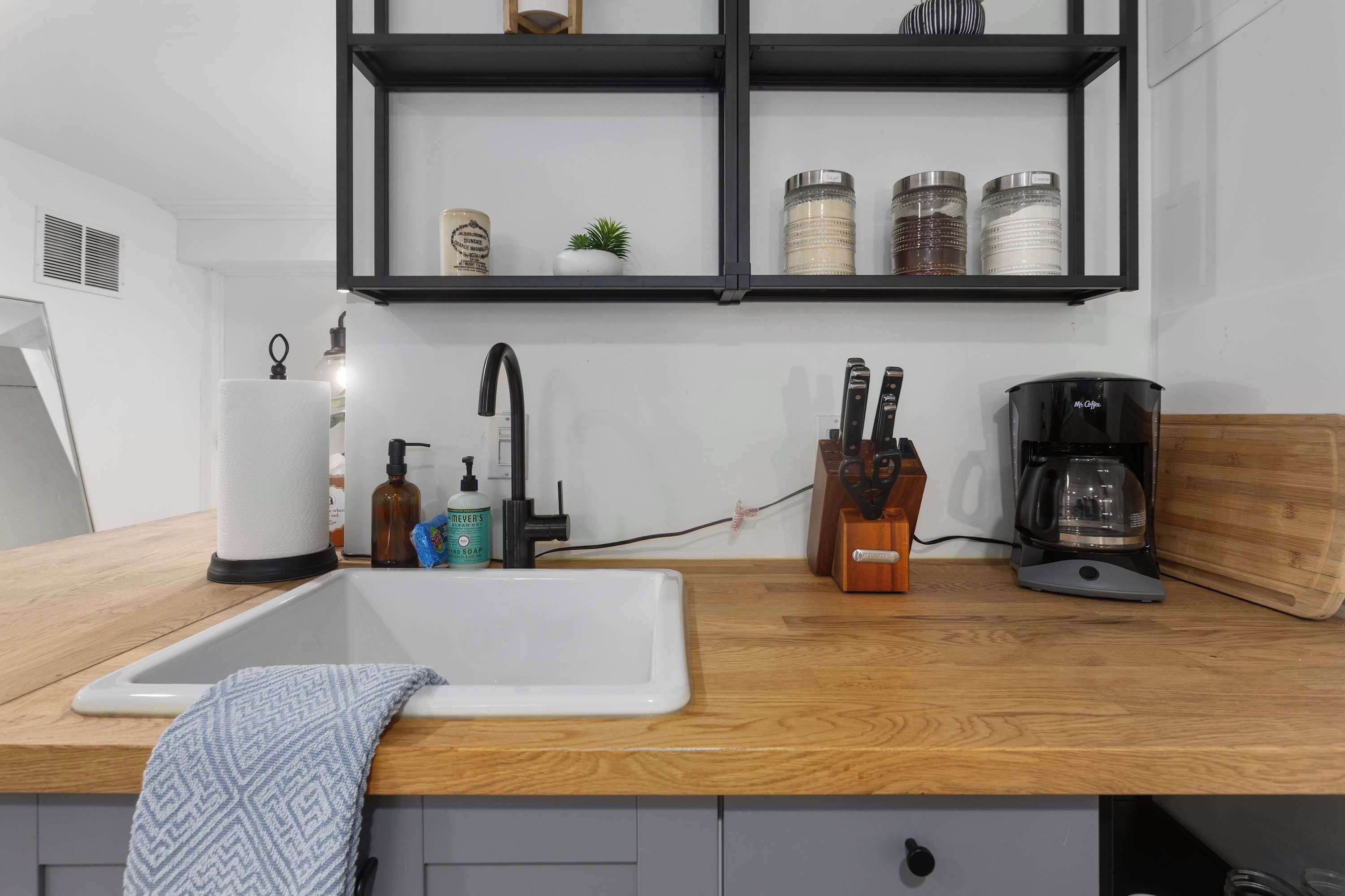 Eine Küche mit weißem Spülbecken, Holzarbeitsplatte und einer Kaffeemaschine.
