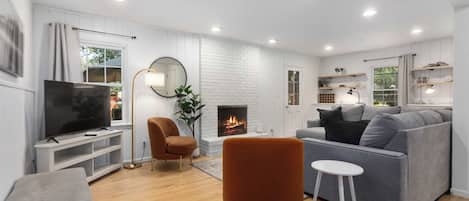 A modern living room with a fireplace, a television, and seating arrangements.