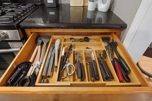 Eine Schublade mit verschiedenen Küchenutensilien, darunter Messer, Pfannenwender und Zangen.