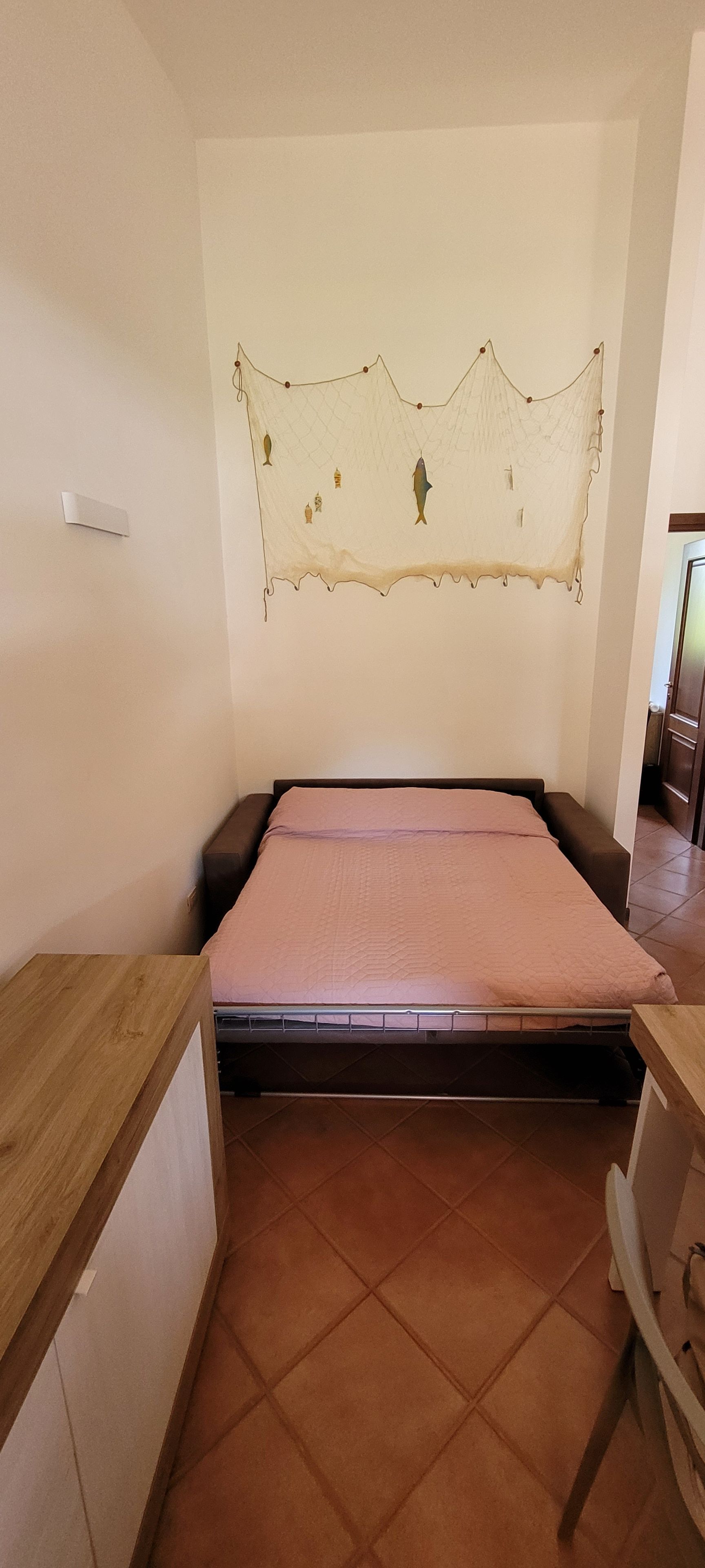 A bedroom with a bed, a wooden desk, and a wall-mounted decoration.