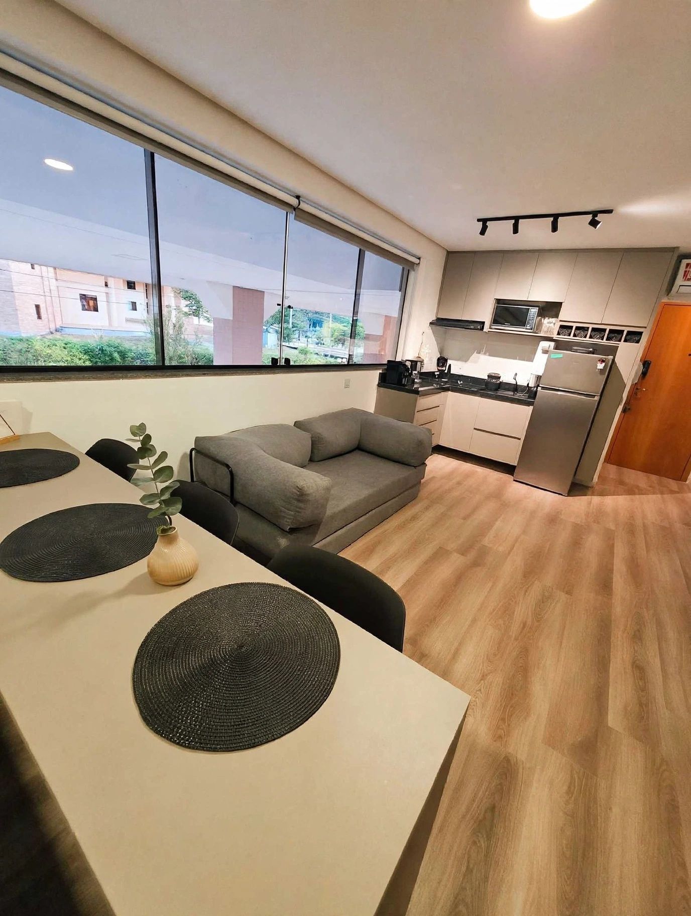 A modern kitchen with a built-in microwave, a refrigerator, and a dining area with a table and chairs.