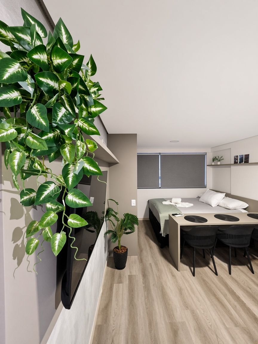 Quarto moderno com cama, mesa de cabeceira e uma grande planta em vaso.