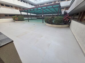 A spacious courtyard with a covered seating area, surrounded by buildings with multiple floors and windows.