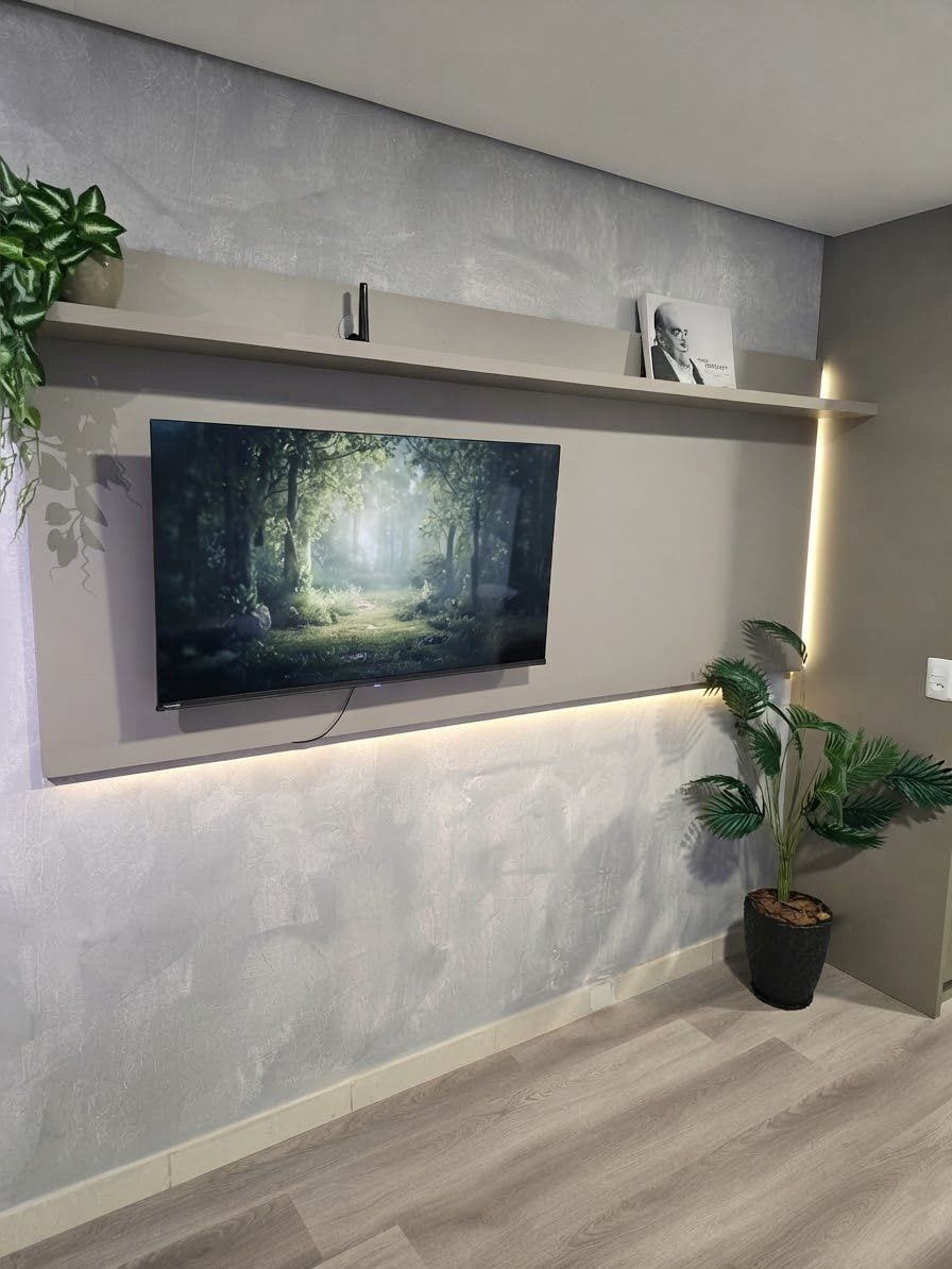 A flat-screen TV mounted on a wall with a shelf above it.