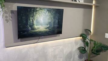 A flat-screen TV mounted on a wall with a shelf above it.