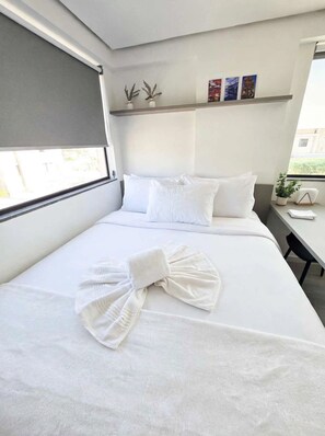 Una habitación de hotel con una cama, un ventanal, un escritorio y una pared decorada con marcos.