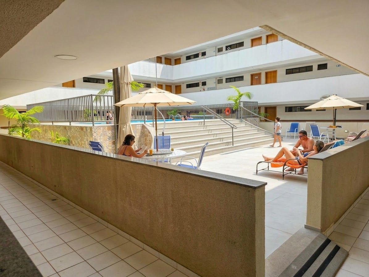 A hotel atrium with a pool, seating areas, and a staircase leading to upper floors.