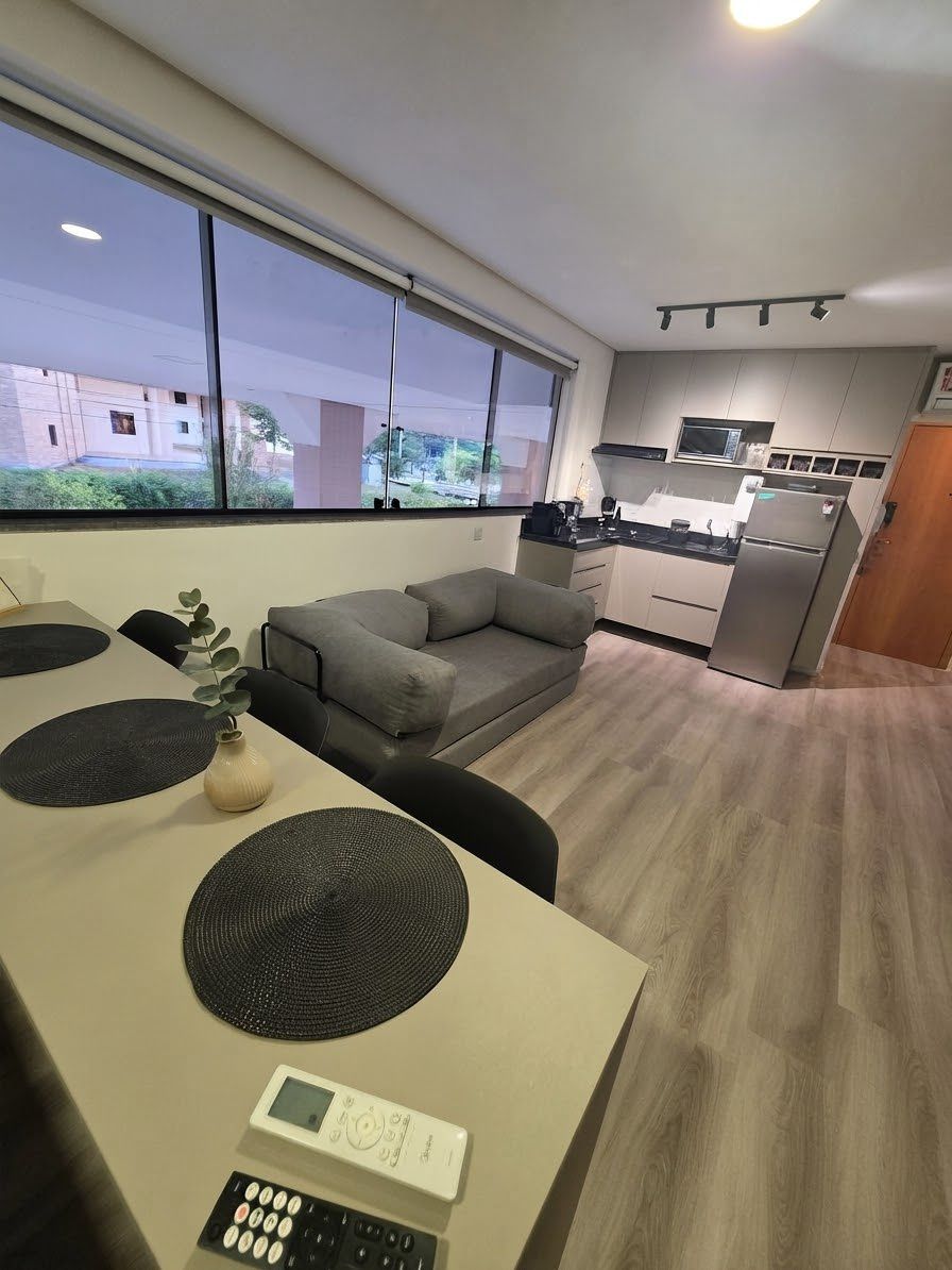 A modern kitchen with a microwave, stove, and refrigerator. There is a dining area with a table and chairs, and a grey sofa.