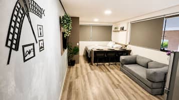 A modern interior with a dining area, sofa, and a wall-mounted light fixture.