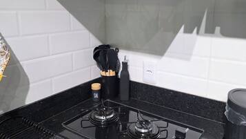 Cozinha com fogão preto, painel de azulejos brancos e exaustor preto.