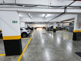Garagem de estacionamento com vários níveis, sinalização direcional clara, piso de concreto e pilares estruturados.