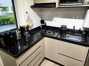 A modern kitchen with a gas stove, coffee maker, and a view of greenery outside.