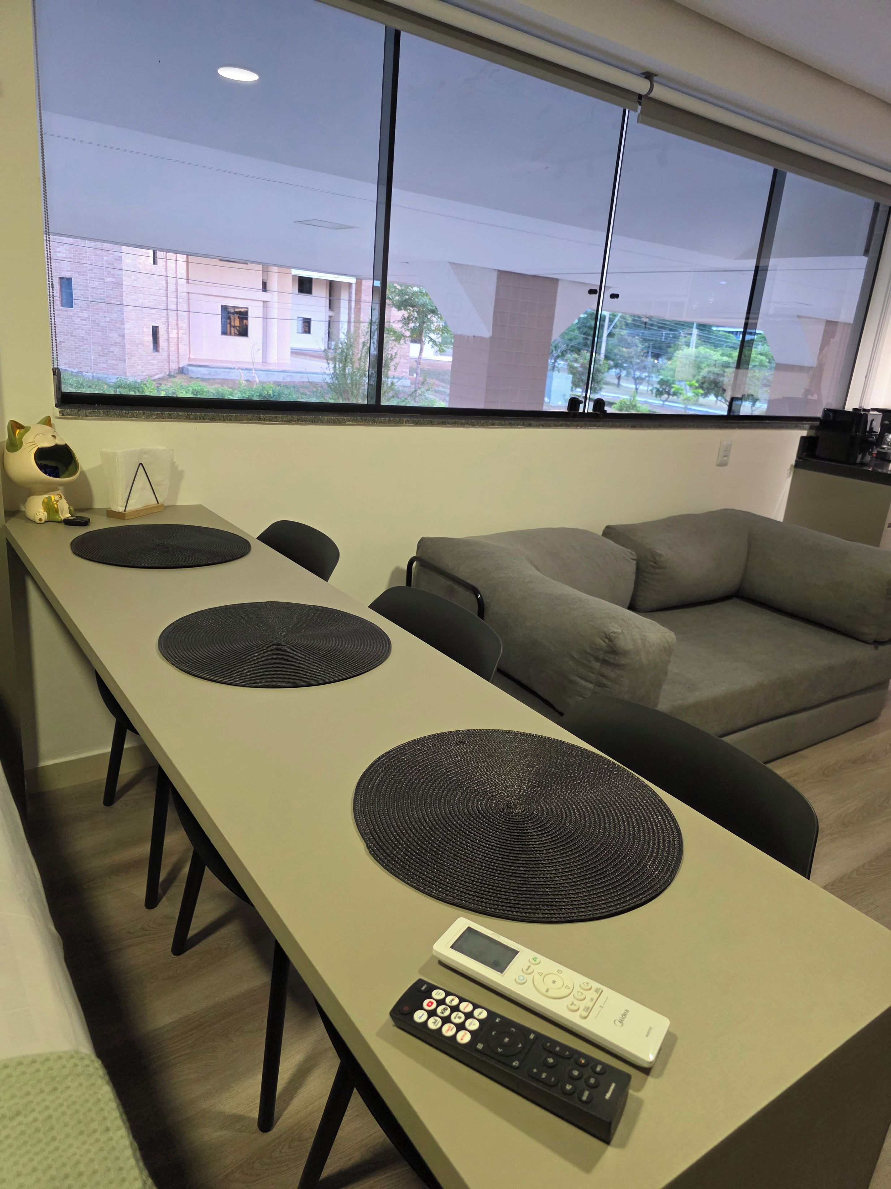 Una sala de estar moderna con comedor, un sofá gris, una mesa de centro y vista a edificios.