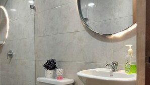 Un baño con inodoro, lavamanos, espejo y planta en maceta.