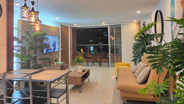 Una sala de estar moderna con sofá, mesa de centro, televisor y plantas.