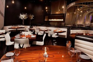 A restaurant interior with booths, round tables, and a central fireplace. - Executive 1BR Yorkville Suite (Toronto)