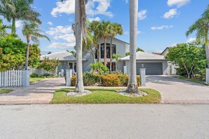 A two-story house with a front yard, a driveway, and a white picket fence. - Waterfront | Boat Rental | Heated Pool | Game Rm | Gym (Lighthouse Point)
