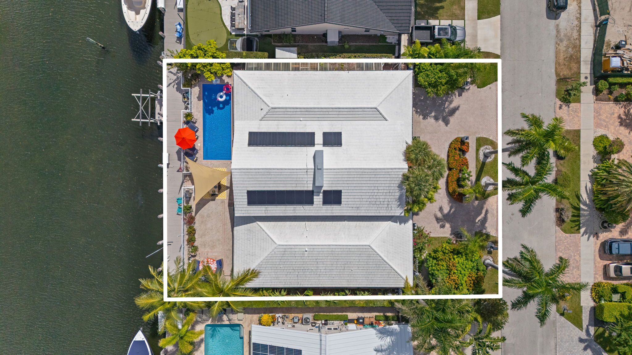 An aerial view of a property with a swimming pool, a covered deck area, and a parking lot.