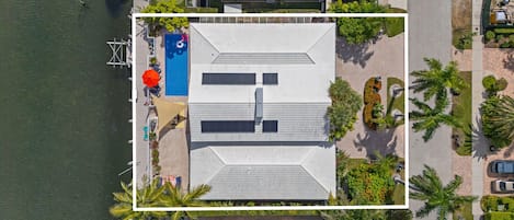 An aerial view of a property with a swimming pool, a covered deck area, and a parking lot.