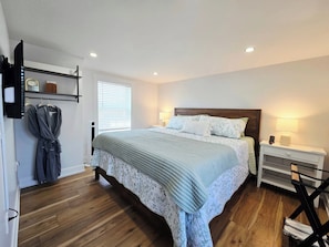 Une chambre à coucher avec un lit, une table de chevet, une lampe et une fenêtre avec des stores.