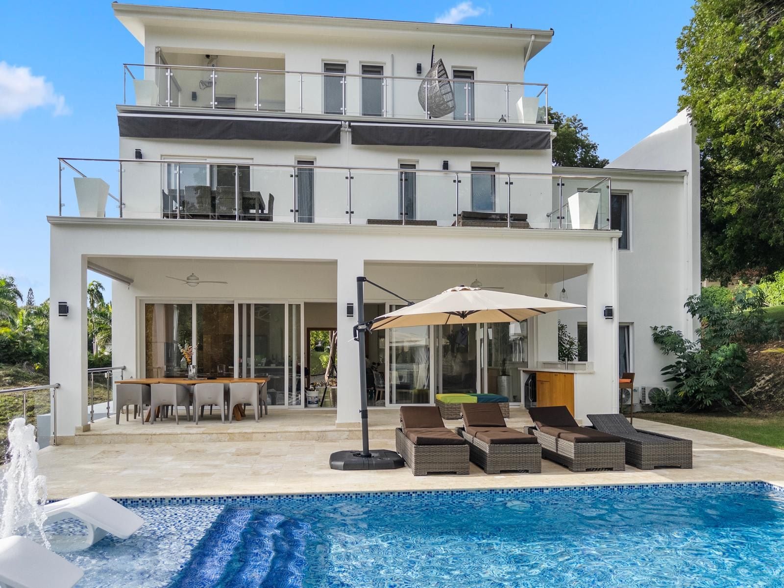 Ein modernes Haus mit zwei Etagen, einem Swimmingpool, Sitzgelegenheiten im Freien und einem Balkon.
