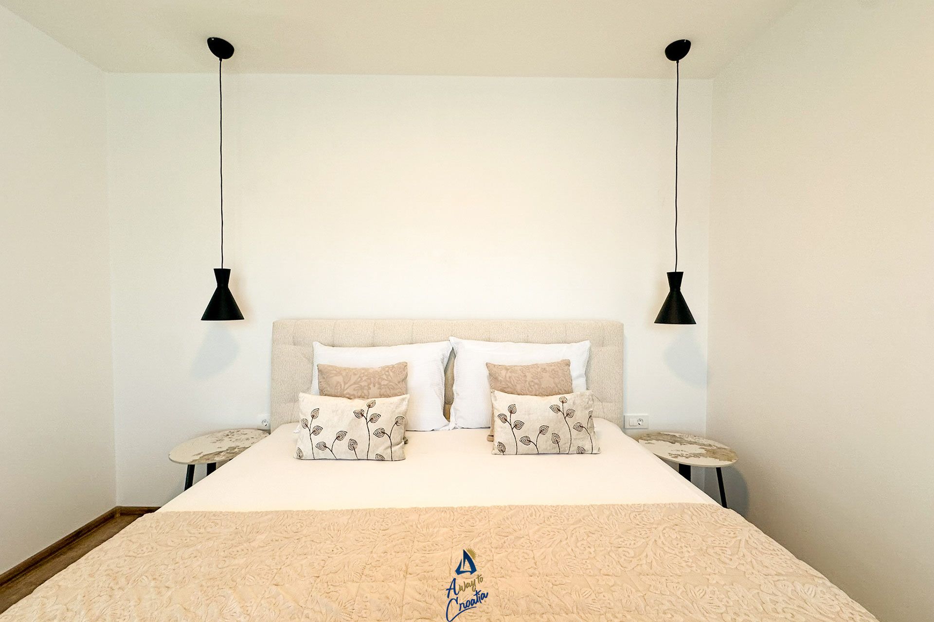 Une chambre à coucher avec un lit, deux tables de chevet et deux lampes suspendues.