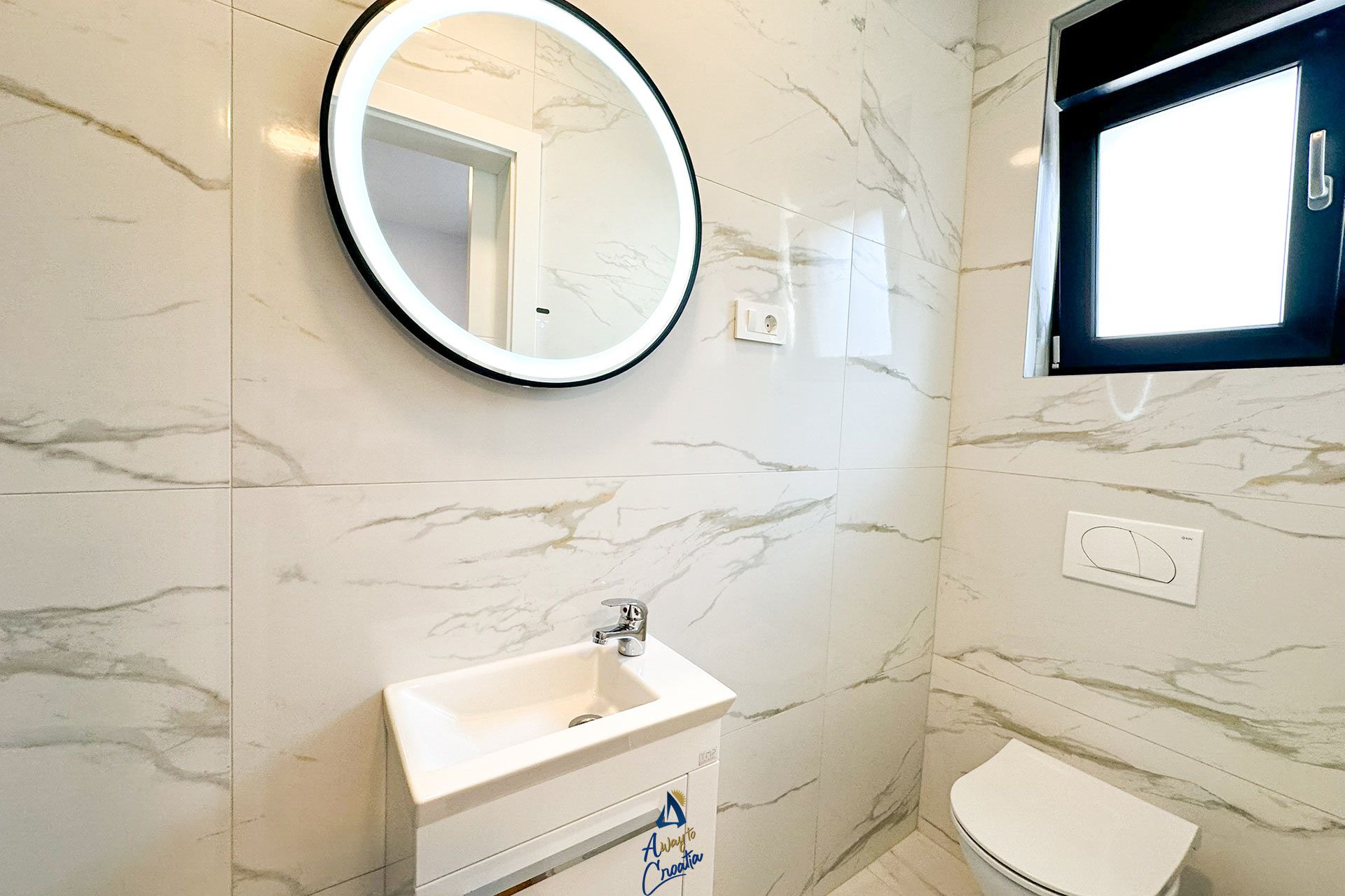 A bathroom with a white sink, a mirror, and a toilet.