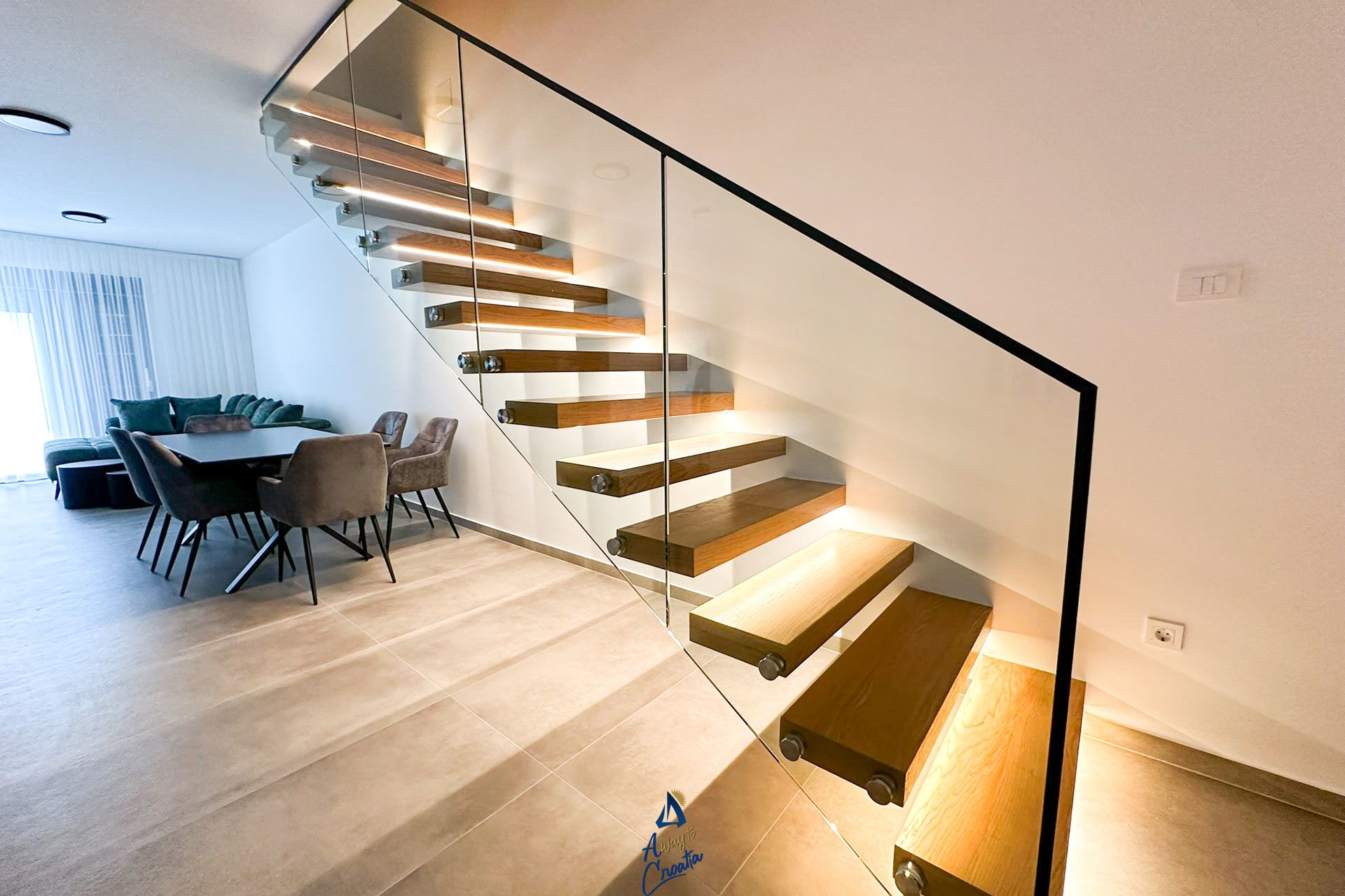Un intérieur moderne avec un escalier, un coin repas et un canapé.