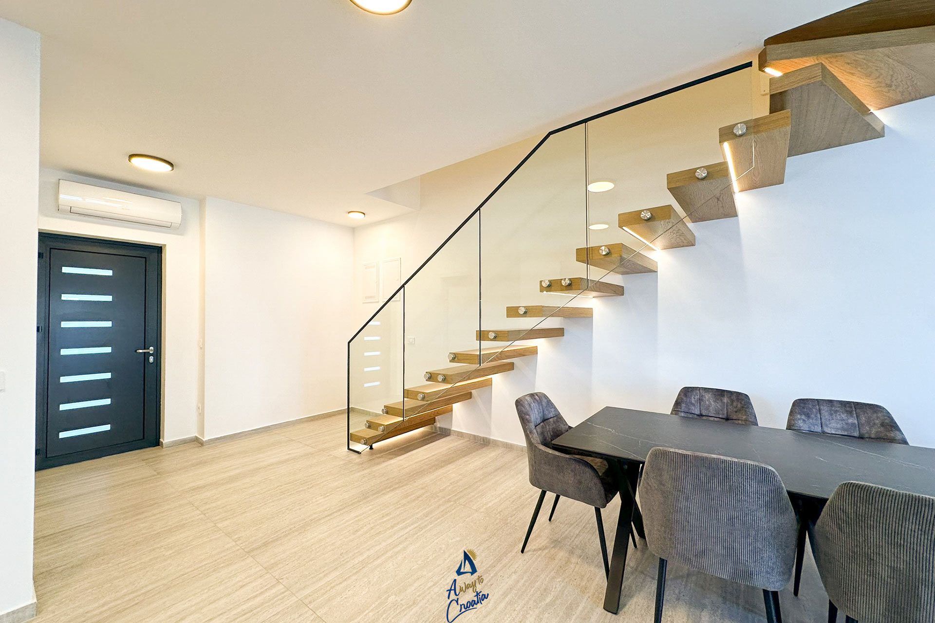 A modern interior with a staircase, a dining area, and a door.