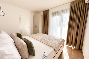 A bedroom with a bed, pillows, a wardrobe, and a window with curtains. - 3-BR Villa with Private Pool Near the Beach (Zaton)